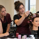 Instructor trainee demonstrates roller placement on a sectioned mannequin while two adult learners watch and an experienced educator supervises.